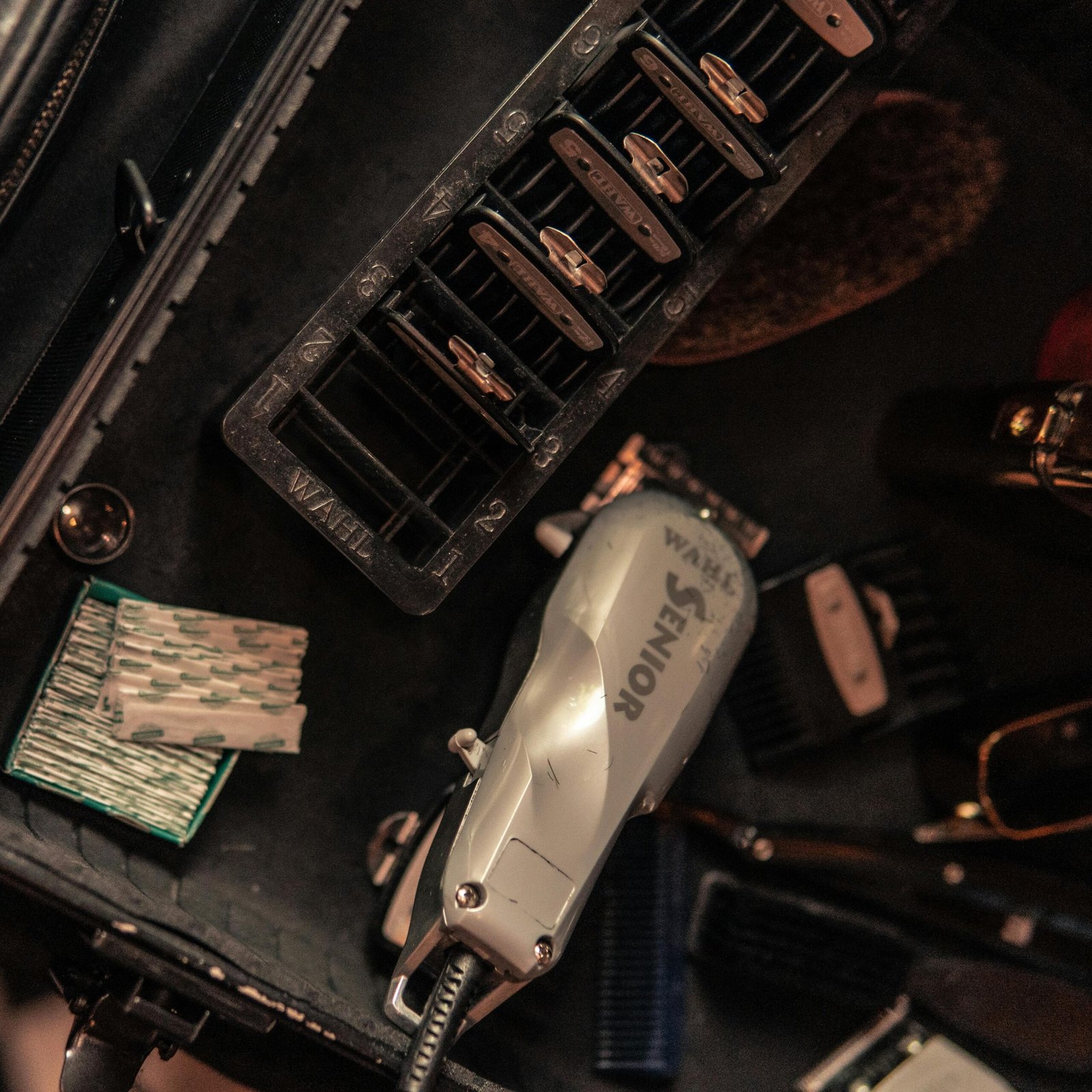 Top view of barber tools including clippers, blades, and accessories on a workstation.